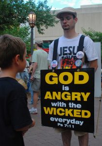man with a sandwichboard sign saying "God is angry with the wicked every day" -- this is not what inviting people looks like