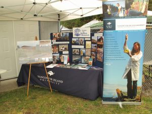 Vancouver Island University booth with branded tablecloth, easel, standing banner, and standing posters